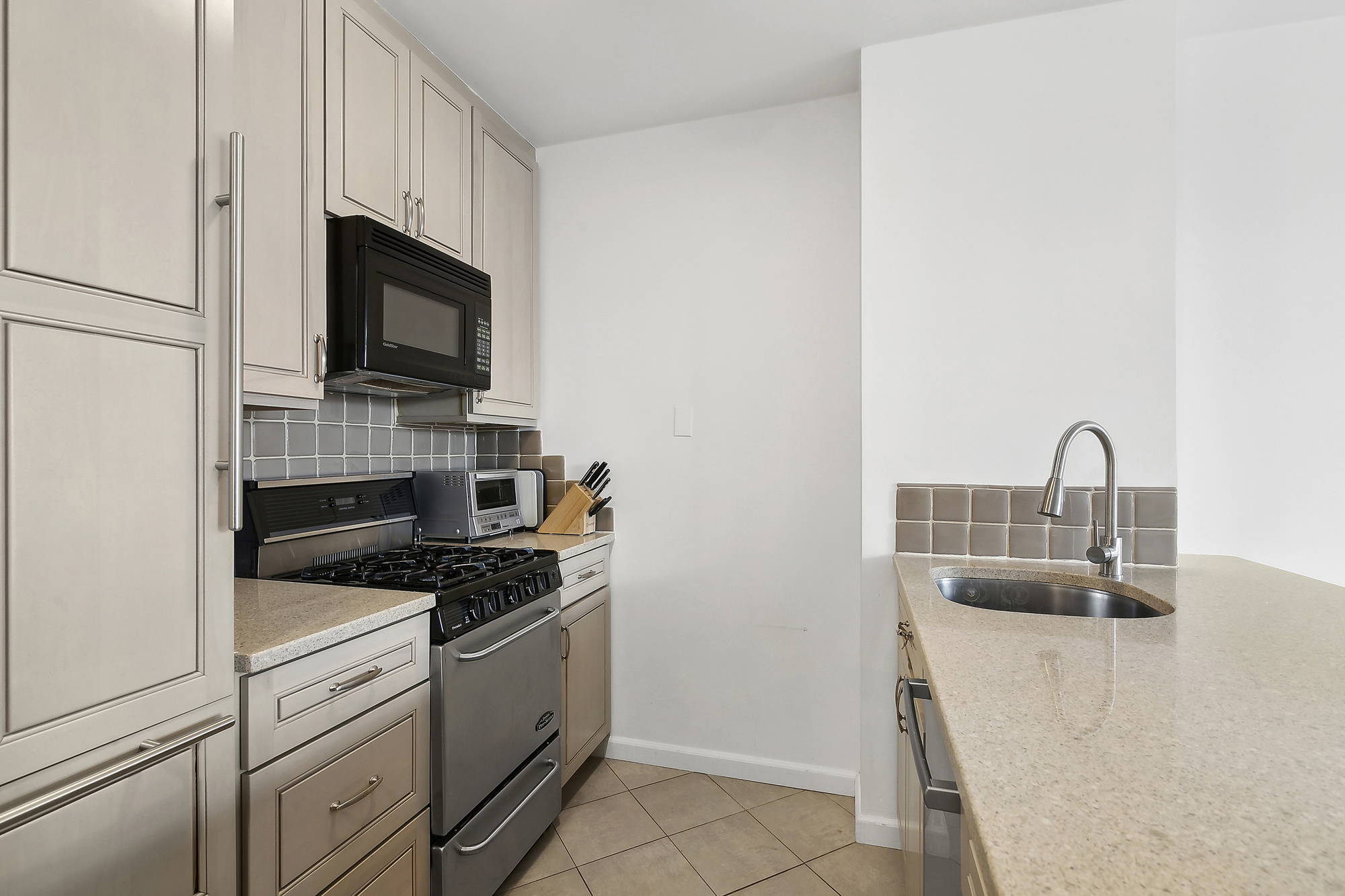 330 East 75th Street, Unit 3J Manhattan, NY 10021 - Photo 2 of 5 a kitchen with white cabinets and stainless steel appliances
