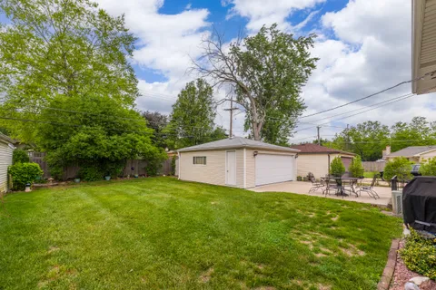 a backyard of a house with table and chairs plants and large tree