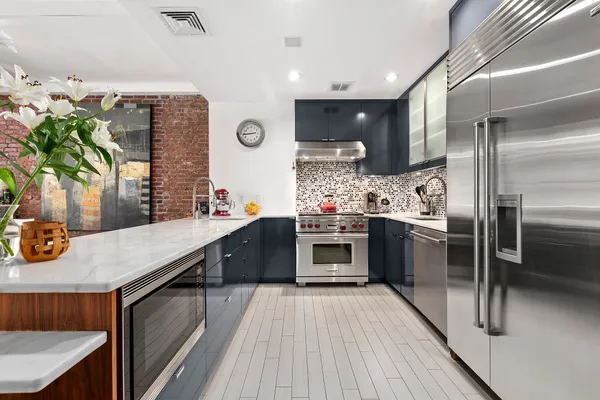 a kitchen with stainless steel appliances kitchen island granite countertop a stove a sink and a refrigerator