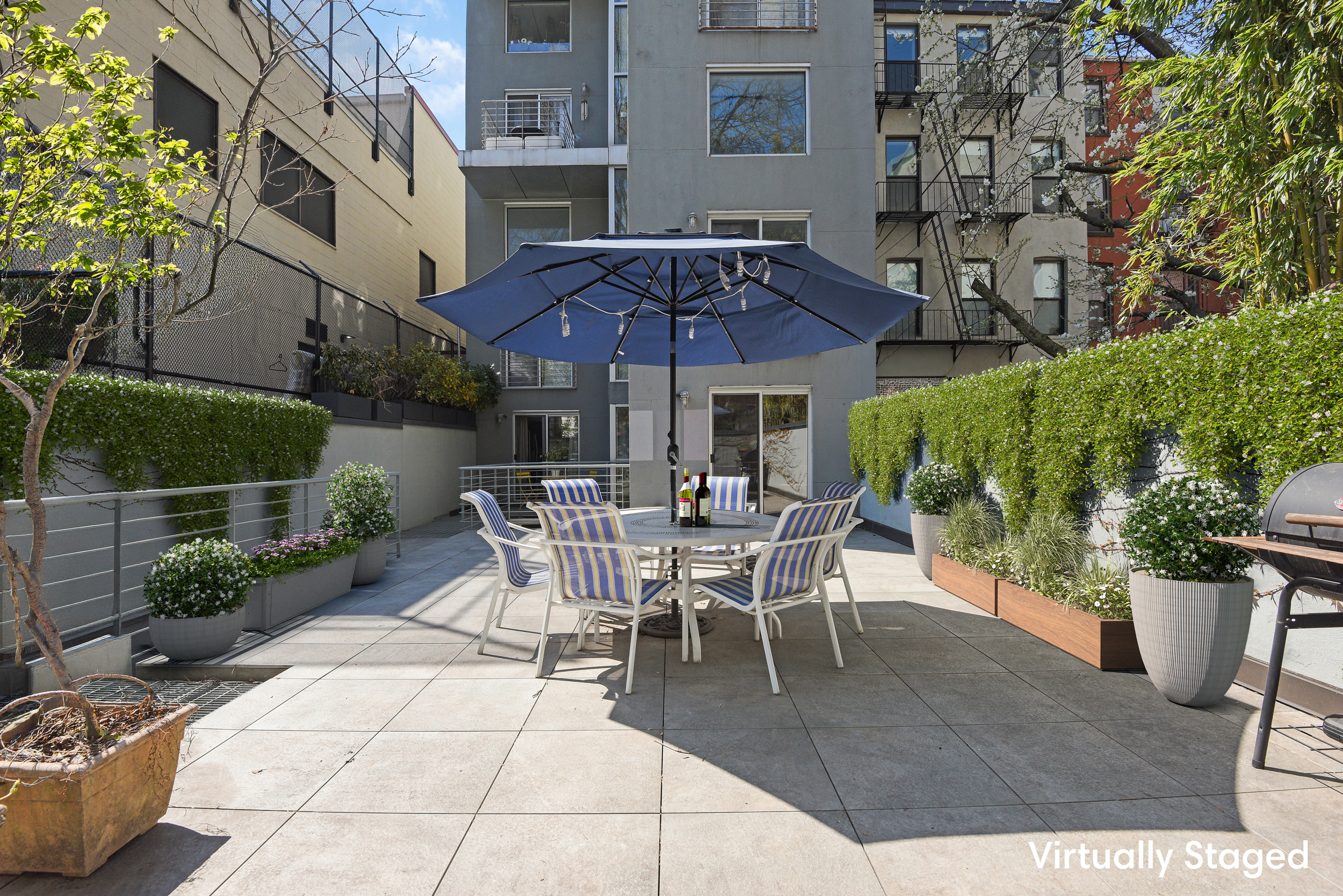 335 Warren Street, Unit 102 Brooklyn, NY 11201 - Photo 19 of 20 a view of a patio with table and chairs potted plants and a barbeque