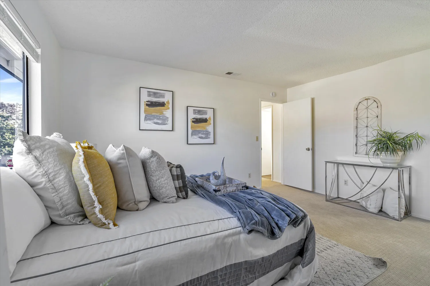 a bedroom with a bed a table and painting on the wall