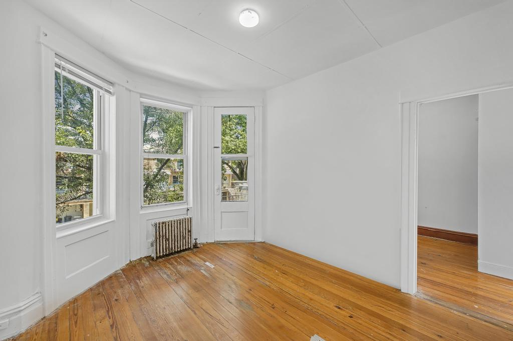10 Seeley Street Brooklyn, NY 11218 - Photo 4 of 27 a view of an empty room with wooden floor and a window