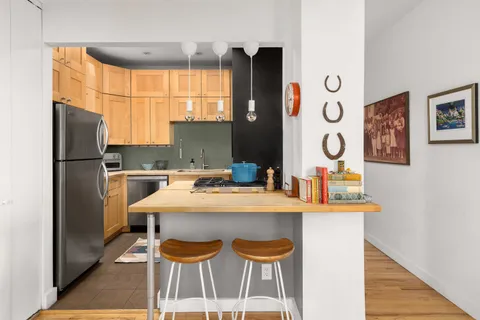 a kitchen with granite countertop a refrigerator a stove a sink and white cabinets with wooden floor