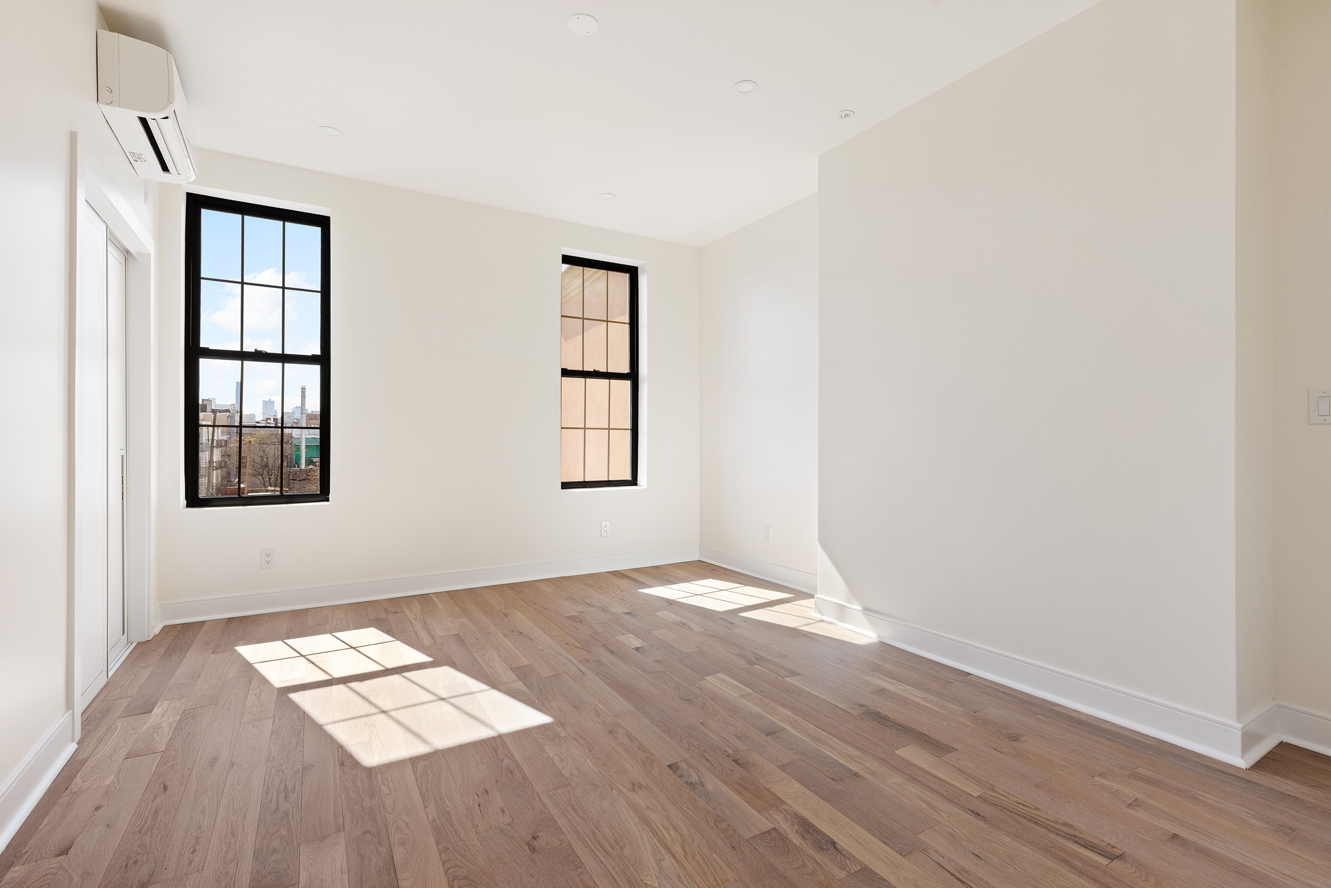 152 North 10th Street, Unit 1L Brooklyn, NY 11249 - Photo 11 of 18 an empty room with wooden floor and windows