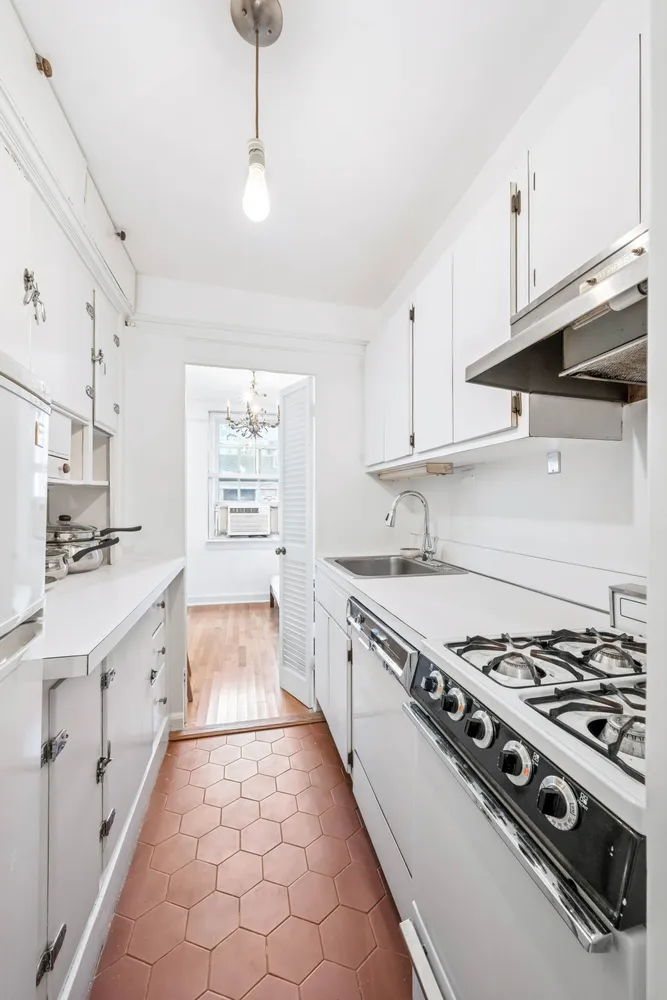 a large white kitchen with stainless steel appliances granite countertop a stove and a sink