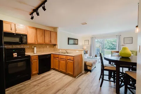 a kitchen with stainless steel appliances granite countertop wooden floors a stove and a center island