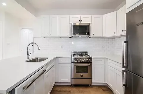 a kitchen with white cabinets and stainless steel appliances