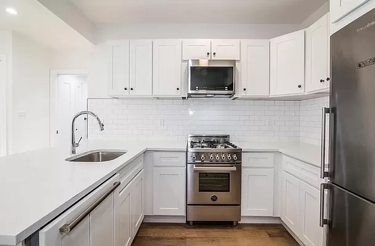 1229 Putnam Avenue, Unit 2D Brooklyn, NY 11221 - Photo 4 of 9 a kitchen with white cabinets and stainless steel appliances