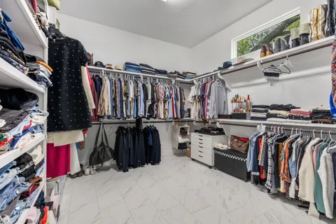 a view of walk in closet with clothes and shoes