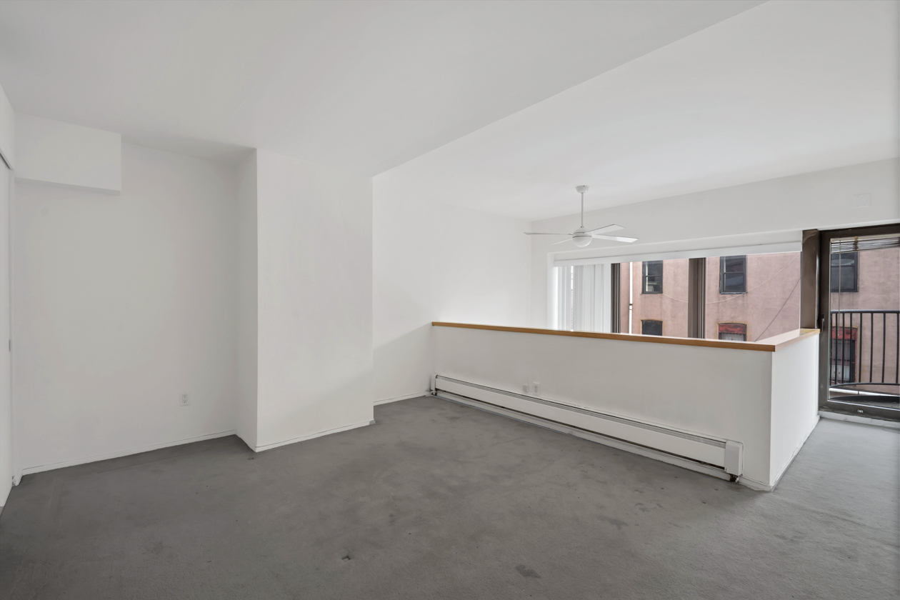 65 Cooper Square, Unit 3D Manhattan, NY 10003 - Photo 5 of 11 a view of an empty room with wooden floor and a kitchen