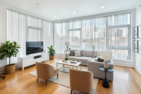 a living room with furniture potted plant wooden floor and a window