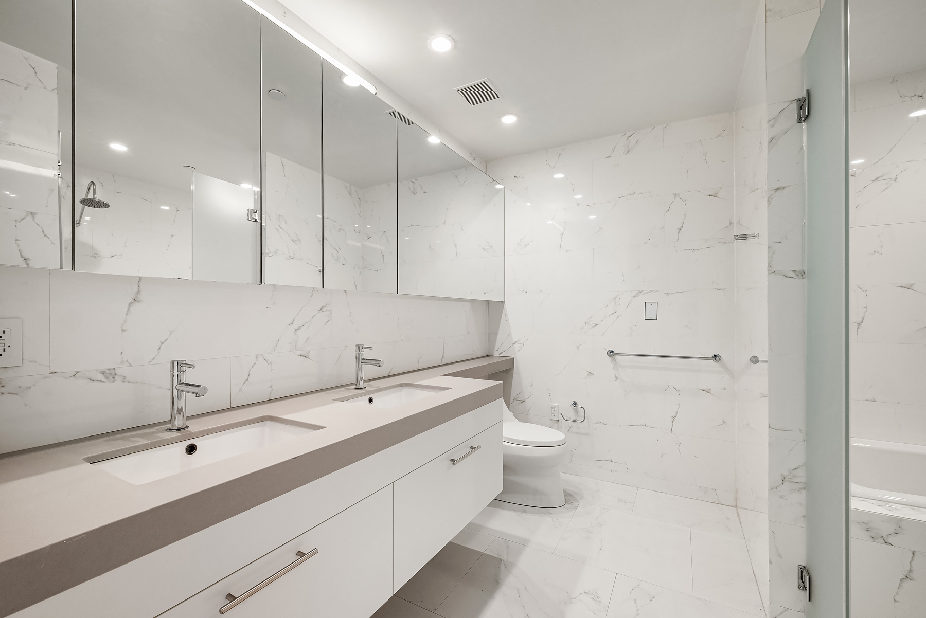 301 East 61st Street, Unit 9B Manhattan, NY 10065 - Photo 5 of 9 a bathroom with a double vanity sink toilet and shower