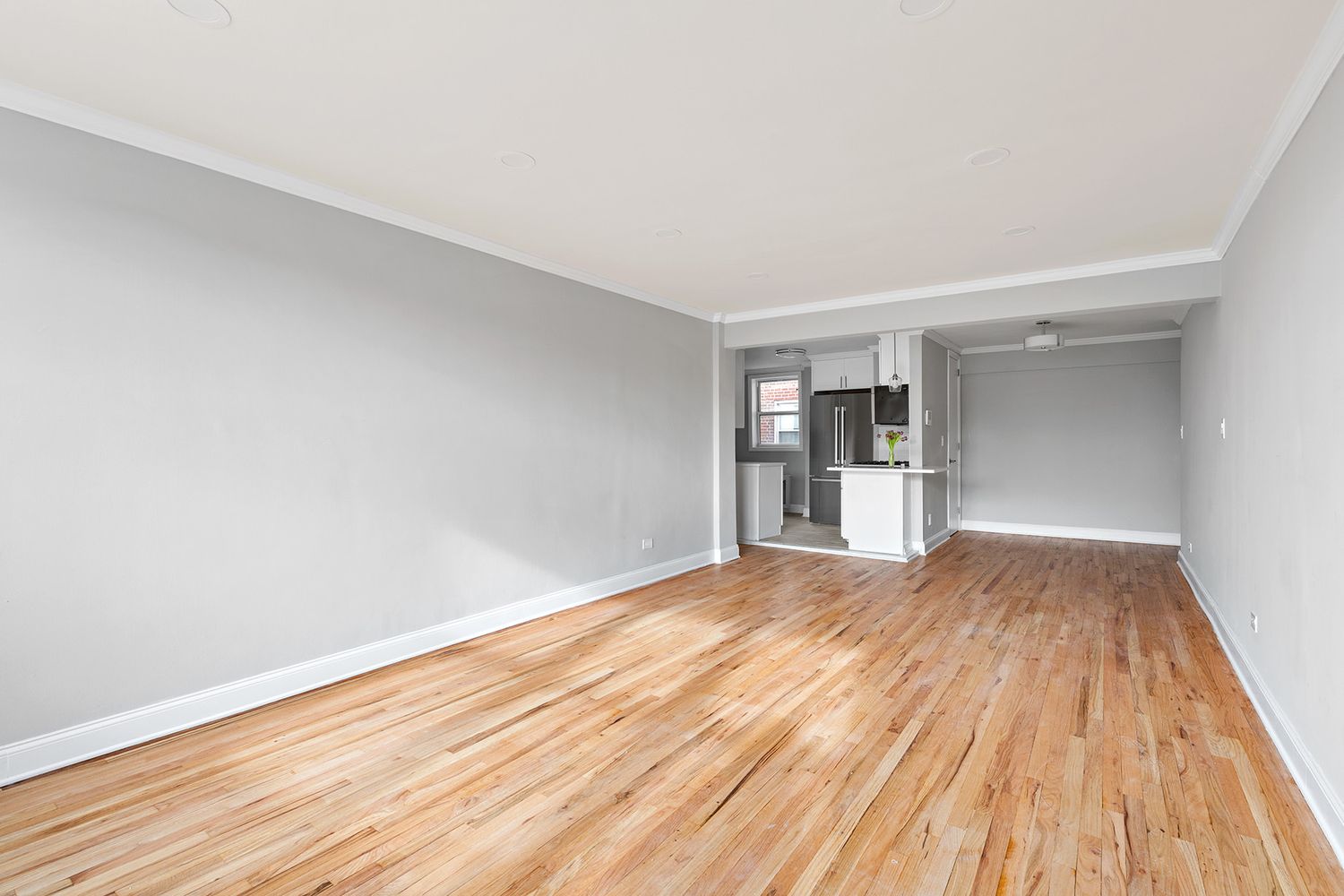 a view of empty room with wooden floor and refrigerator