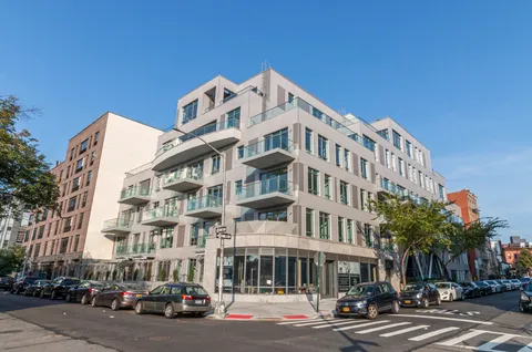 a front view of a building with lot of cars and trees