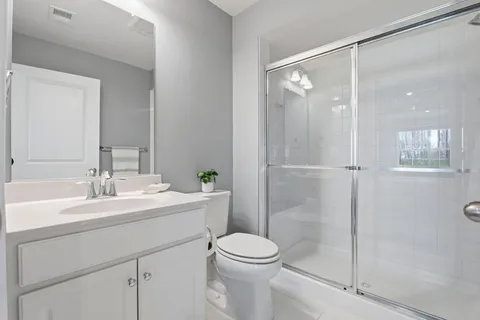 a bathroom with a shower sink vanity mirror and toilet