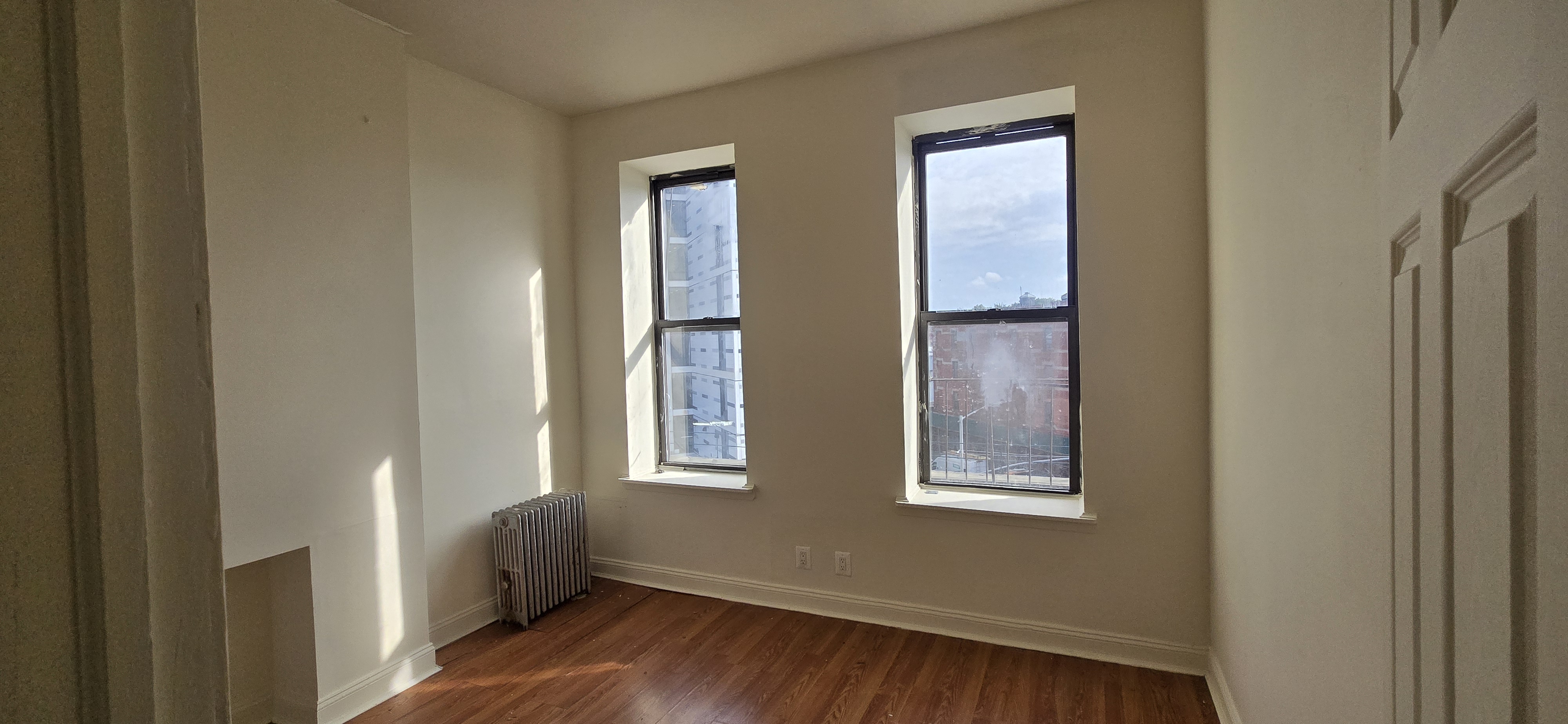 1501 Broadway, Unit 4 Brooklyn, NY 11221 - Photo 2 of 7 a view of an empty room with wooden floor and a window
