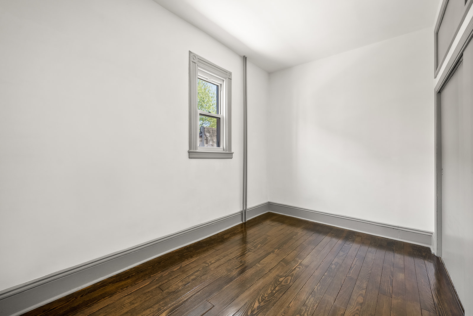 59-45 Palmetto Street Queens, NY 11385 - Photo 7 of 25 a view of an empty room with wooden floor and a window
