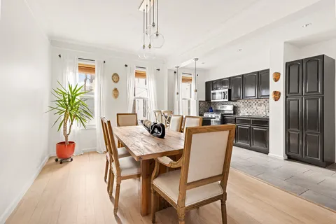 a dining room with furniture a chandelier and kitchen view