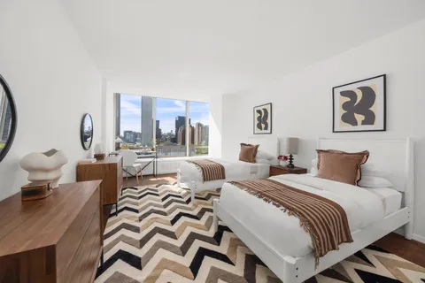 a bedroom with two beds and a large mirror next to a window