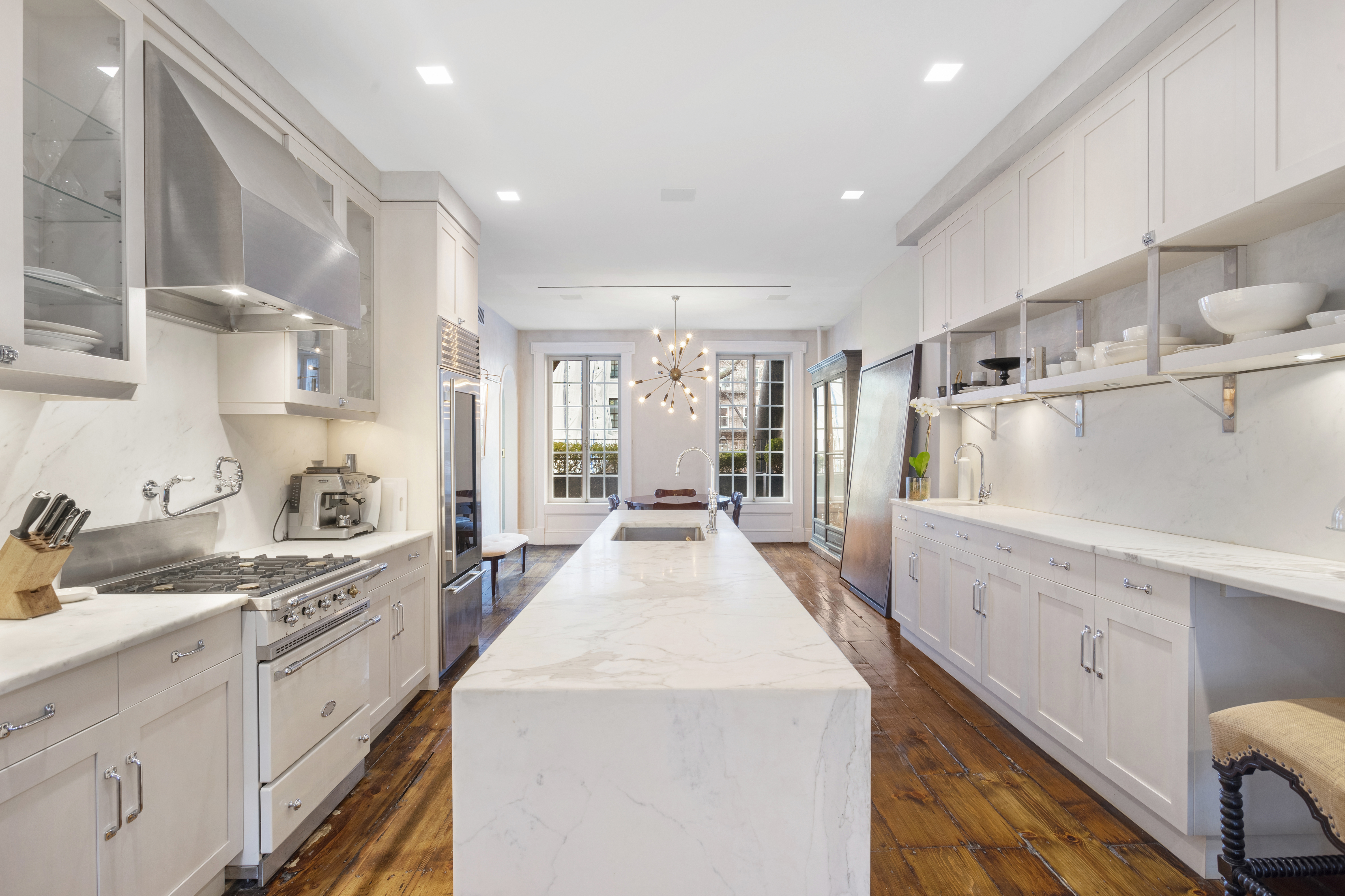 75 Washington Place, Unit TRIPLEX Manhattan, NY 10011 - Photo 1 of 14 a view of a kitchen with kitchen island a stove a sink dishwasher and white cabinets with wooden floor