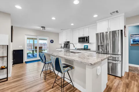 a kitchen with stainless steel appliances granite countertop a dining table chairs refrigerator microwave and cabinets