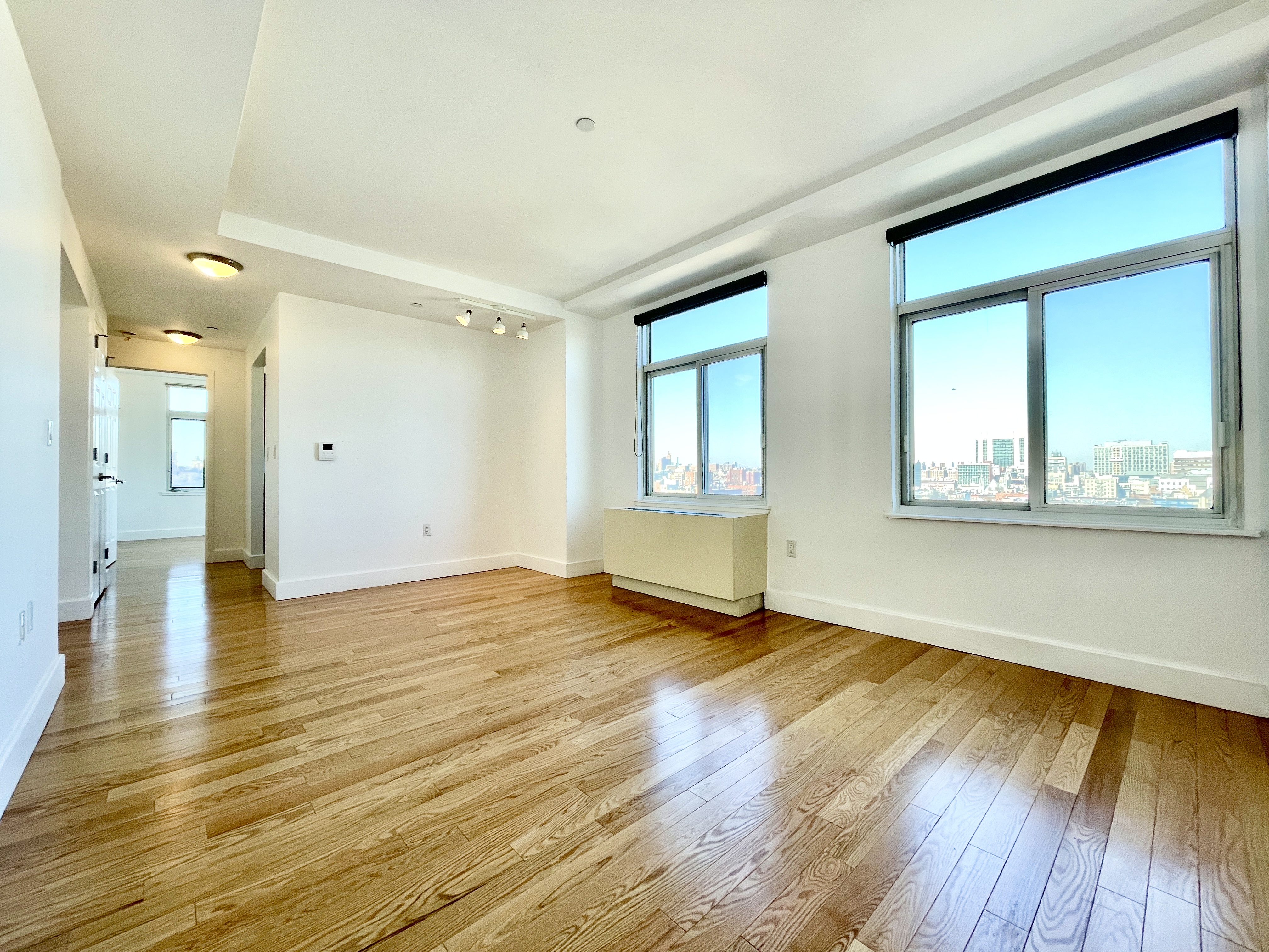 a view of an empty room with wooden floor and a window