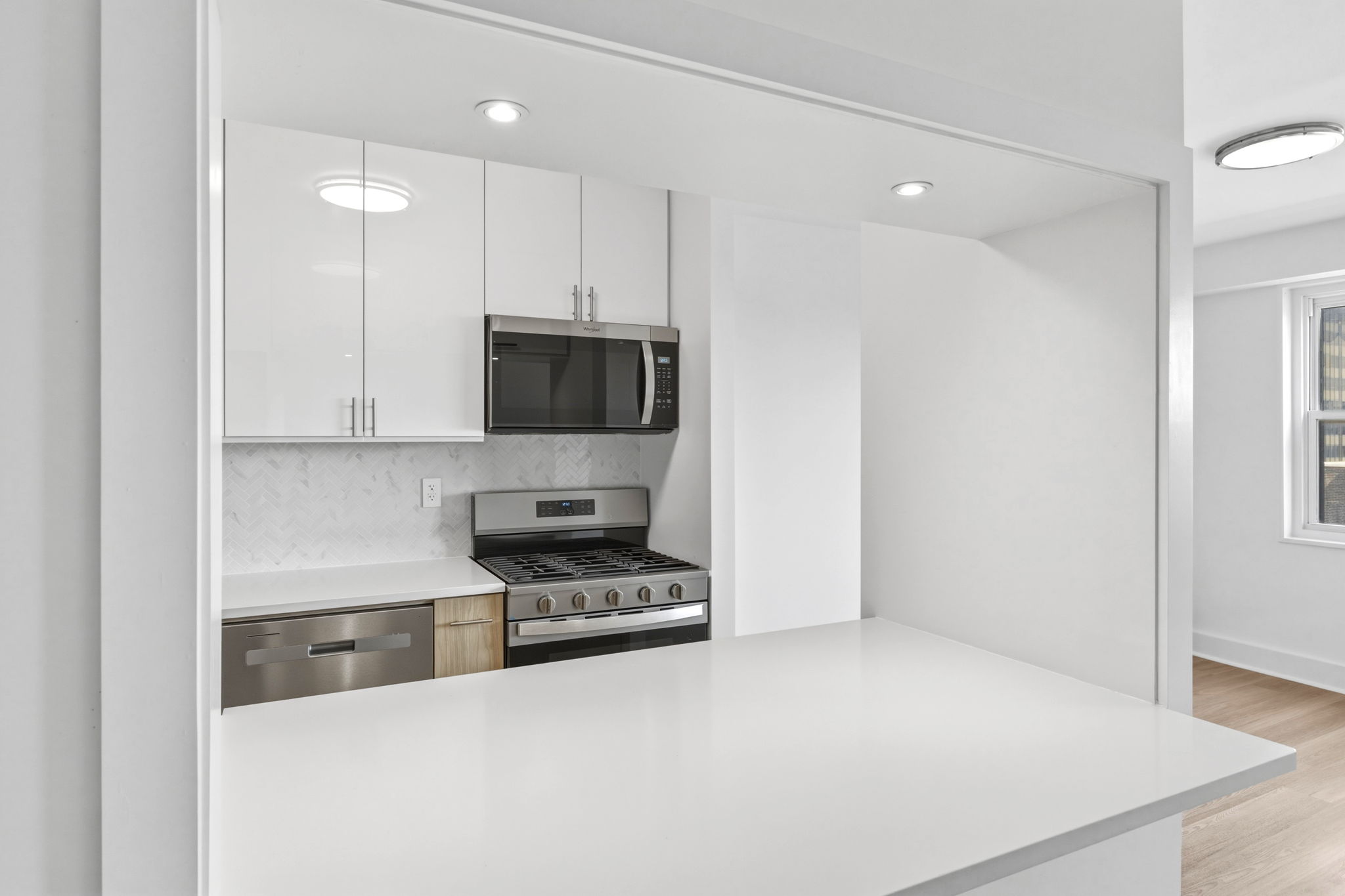 400 East 54th Street, Unit 24E Manhattan, NY 10022 - Photo 10 of 29 a kitchen with stainless steel appliances a stove a microwave and white cabinets