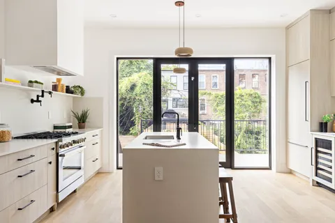 a room with kitchen island a large window a sink and cabinets