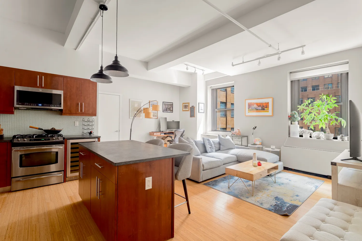 a kitchen with stainless steel appliances granite countertop a stove refrigerator and couches with wooden floor