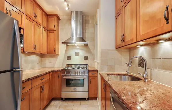 a kitchen with stainless steel appliances granite countertop a sink a stove and a refrigerator