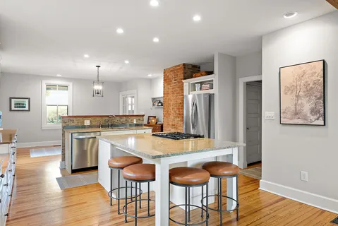 a kitchen with stainless steel appliances granite countertop a kitchen island and chairs in it