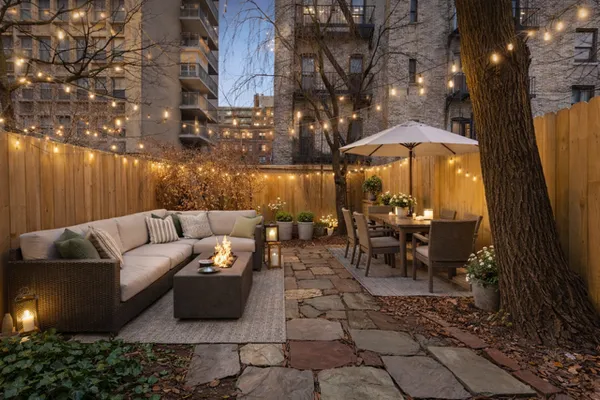 a view of a patio with couches table and chairs under an umbrella with a fire pit