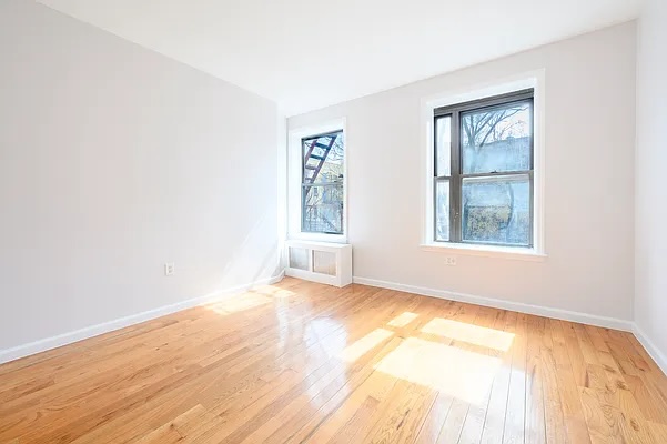 237 West 135th Street, Unit 3A Manhattan, NY 10030 - Photo 10 of 12 an empty room with wooden floor and windows