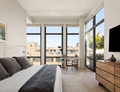 a bedroom with a bed and large windows