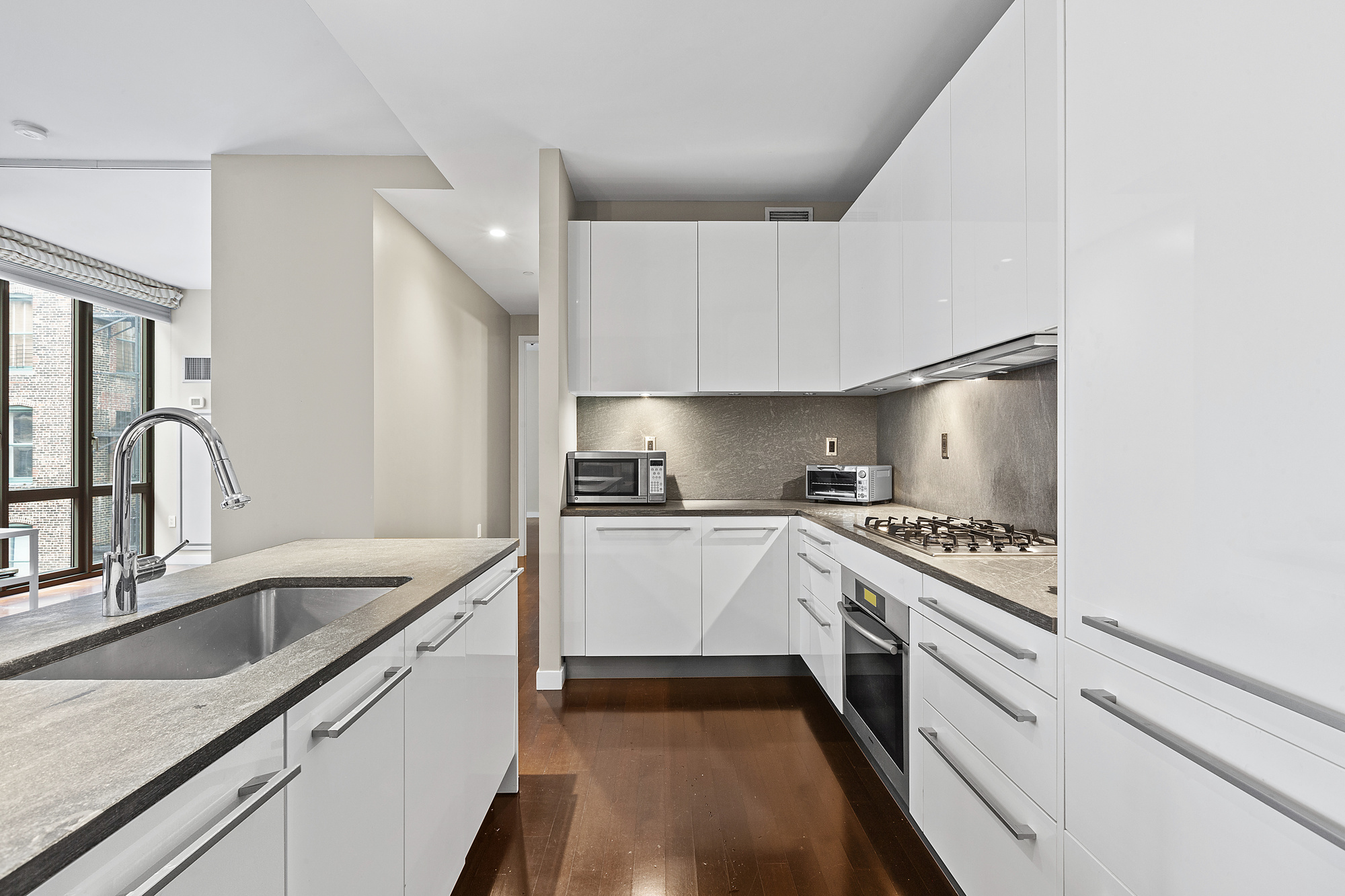 4 West 21st Street, Unit 11A Manhattan, NY 10010 - Photo 2 of 9 a kitchen with granite countertop white cabinets and white appliances