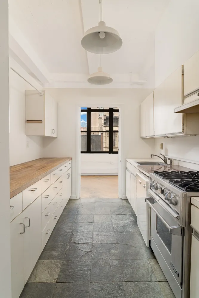 a large white kitchen with stainless steel appliances granite countertop a stove and a sink