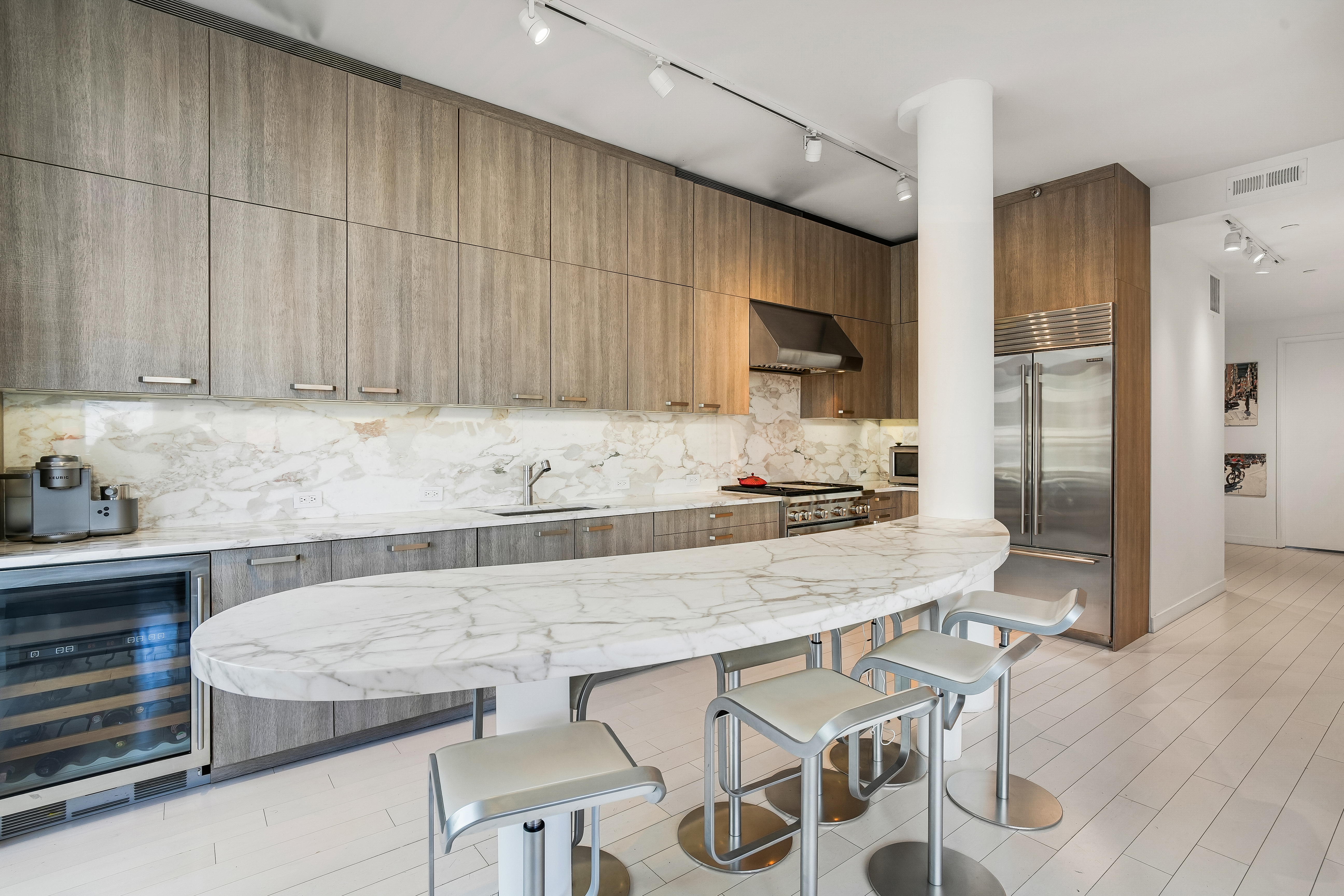 450 East 83rd Street, Unit 6B Manhattan, NY 10028 - Photo 8 of 25 a kitchen with stainless steel appliances kitchen island granite countertop a table chairs in it and wooden floors