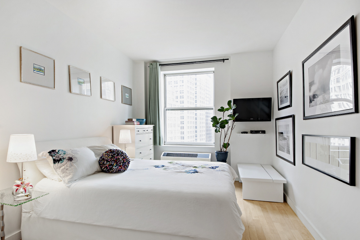 15 Broad Street, Unit 2506 Manhattan, NY 10005 - Photo 4 of 23 a bedroom with a bed a large window and a flat screen tv