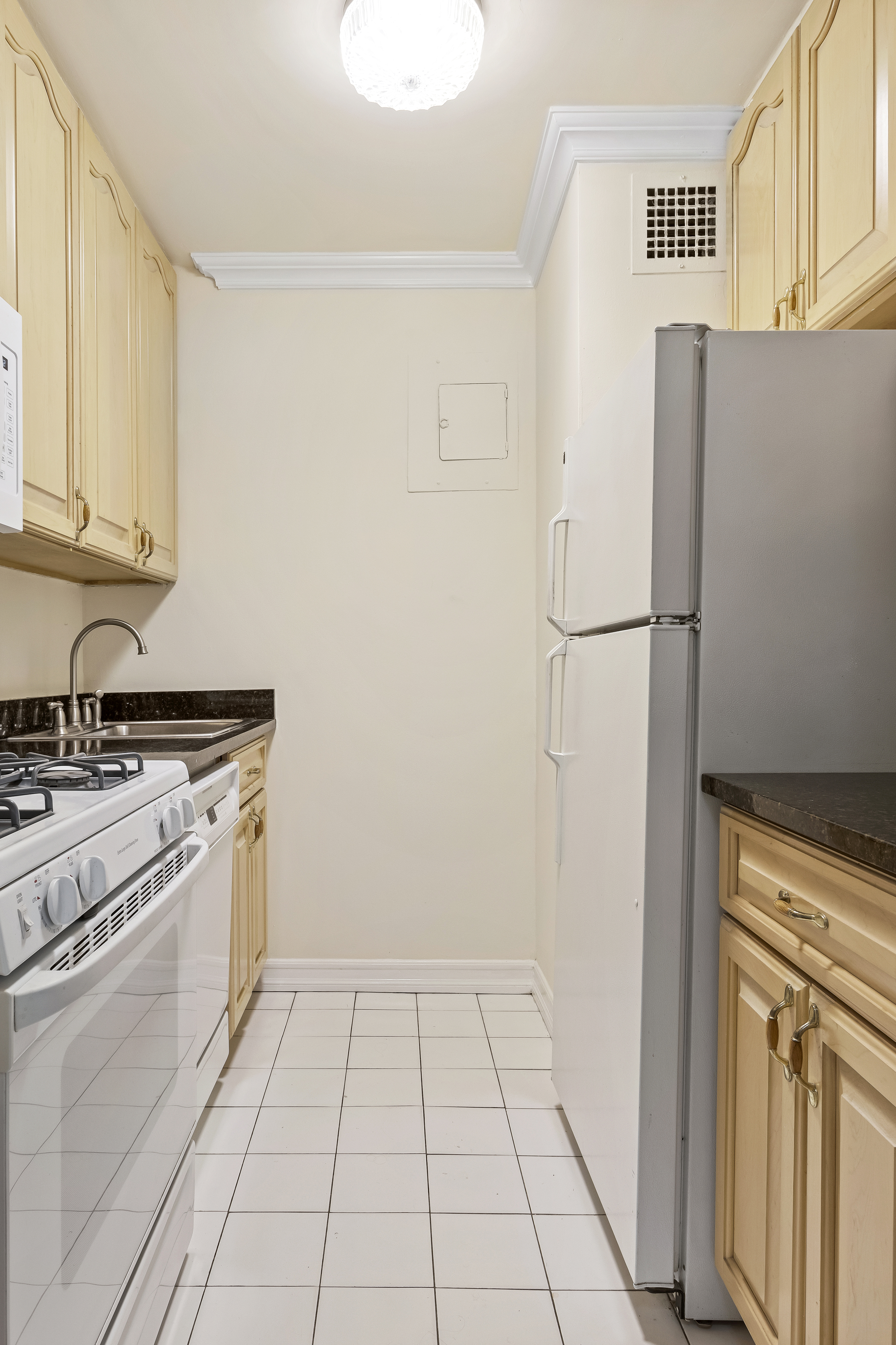 301 East 79th Street, Unit 31F Manhattan, NY 10075 - Photo 4 of 6 a kitchen with white cabinets and white appliances