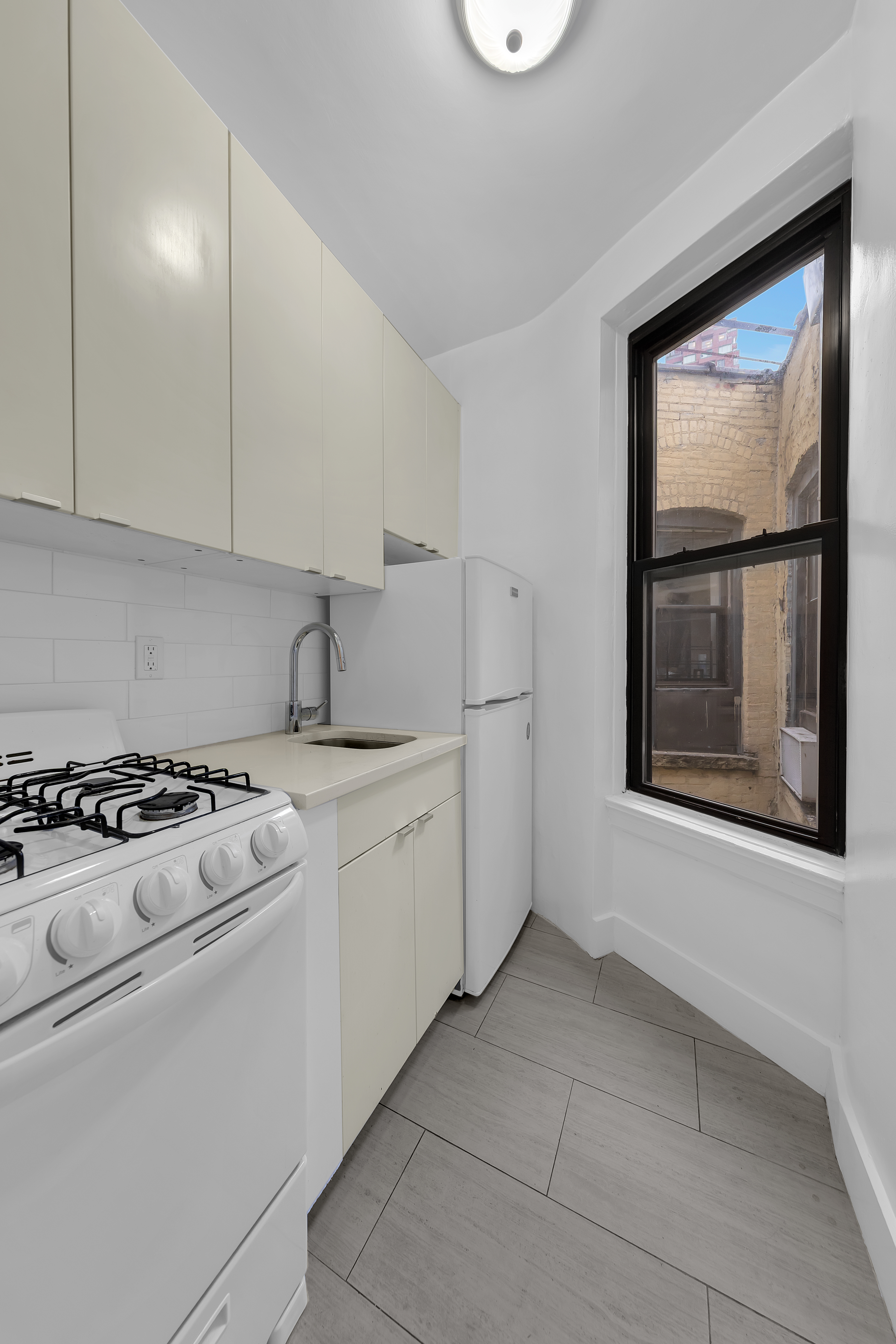 370 Columbus Avenue, Unit 5D Manhattan, NY 10024 - Photo 4 of 10 a kitchen with a stove a sink and a window