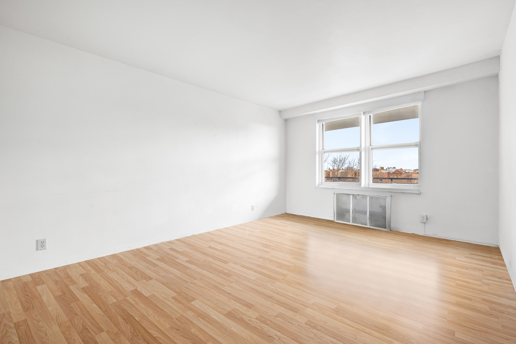 35-50 85th Street, Unit 9J Queens, NY 11372 - Photo 8 of 11 an empty room with wooden floor and windows