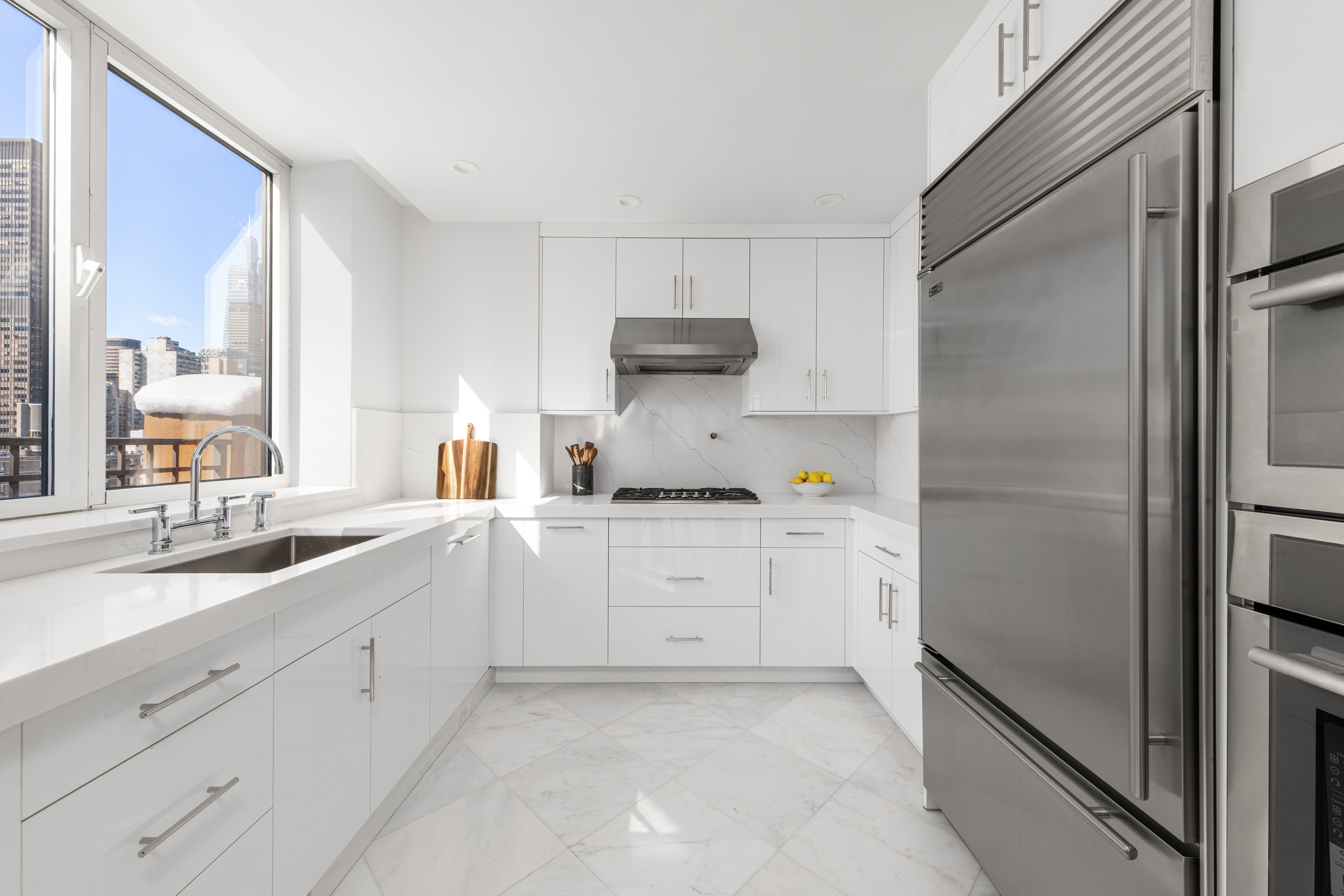 351 East 51st Street, Unit PH5B Manhattan, NY 10022 - Photo 3 of 13 a kitchen with white cabinets and a refrigerator