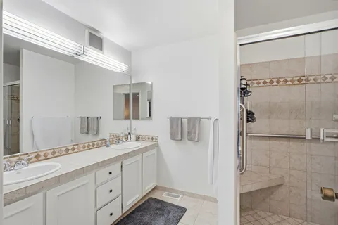 a spacious bathroom with a double vanity sink a mirror and shower