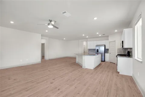 a view of kitchen with kitchen island stainless steel appliances refrigerator stove top oven and cabinets