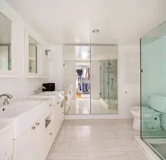 a large white bathroom with a tub sink mirror and shower