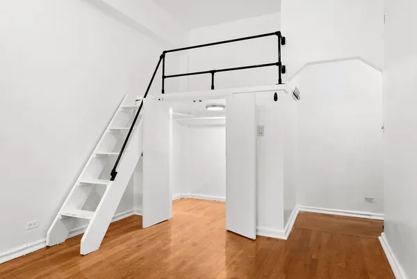 a view of an empty room with wooden floor and stairs