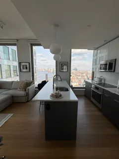 a living room with furniture kitchen view and a large window