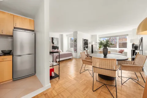 a living room with furniture a dining table and a refrigerator