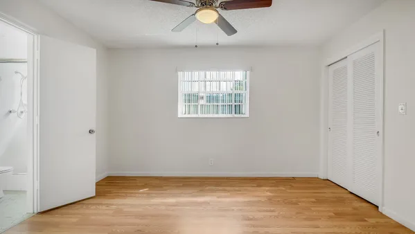 a view of an empty room with window and wooden floor