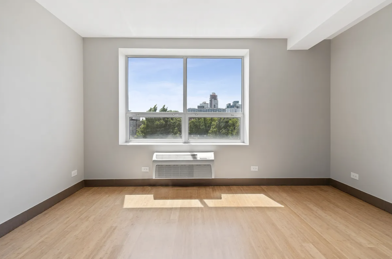 5-43 48th Avenue, Unit 5E Queens, NY 11101 - Photo 6 of 9 a view of an empty room with a window and wooden floor